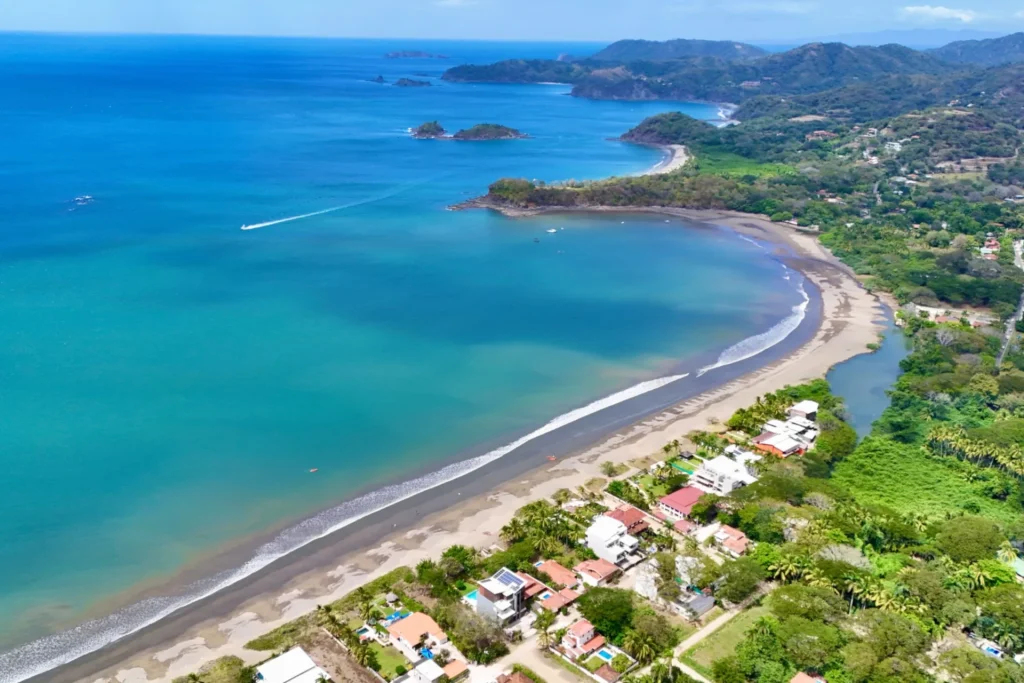 Aerial view of Playa Potrero's curved bay and beach, with offshore islands and the green hills of Guanacaste, Costa Rica