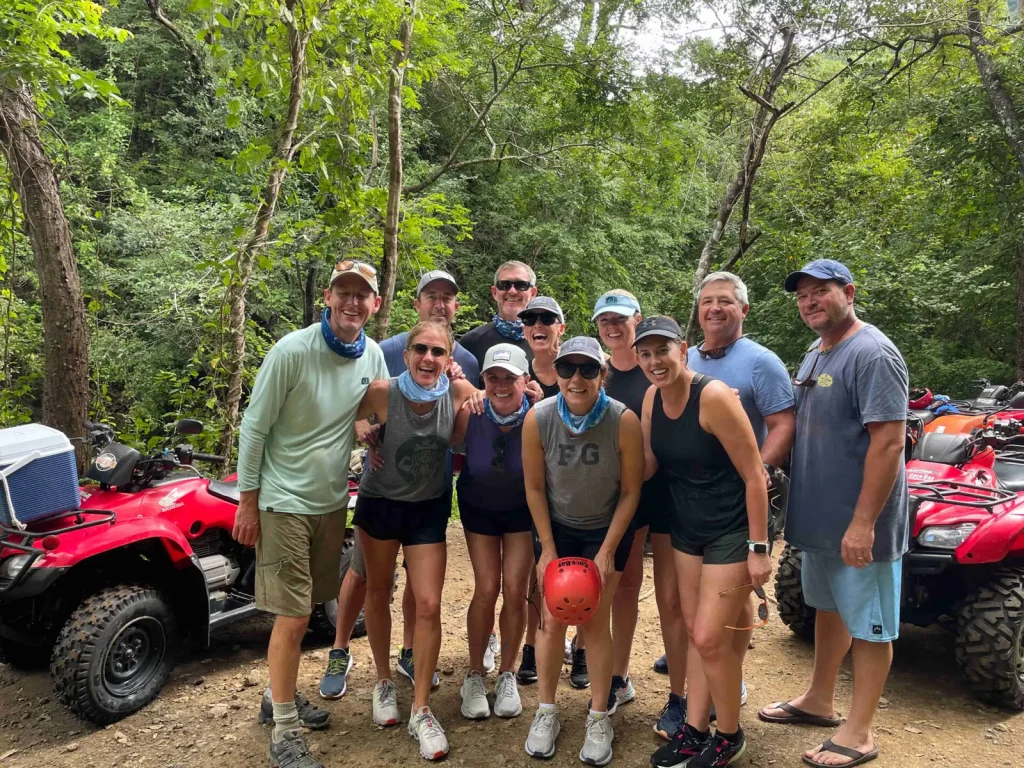 A happy tour group posing with their ATVs on a jungle trail during an ATV adventure near Playa Potrero