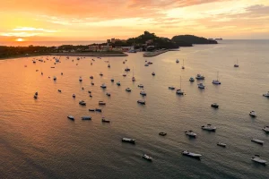 Aerial view of Flamingo Marina at sunset, with fishing boats and sailboats anchored in the bay off Playa Flamingo, Guanacaste, Costa Rica
