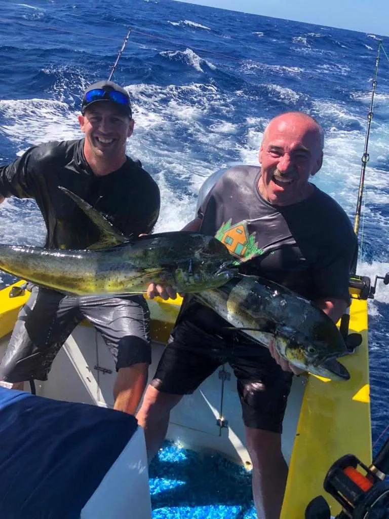 Two anglers grinning as they hold up a pair of mahi-mahi caught offshore on a Fish Potrero charter near Playa Potrero