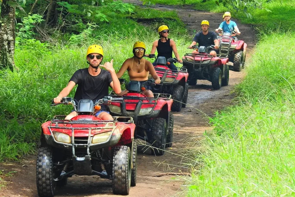A group of tourists riding red ATVs on a jungle trail through the Guanacaste countryside near Playa Potrero