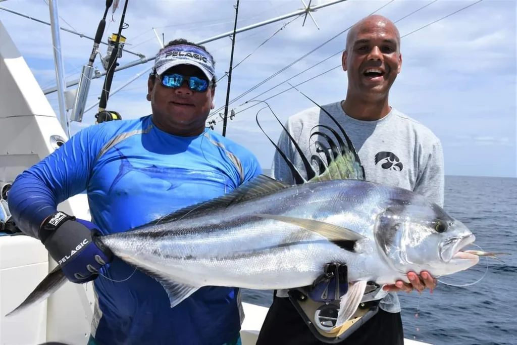 Smiling angler and captain with a roosterfish caught inshore aboard a Fish Potrero charter, rods and rigging visible behind them