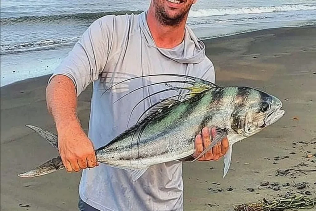 An angler holding a roosterfish caught from shore on a Playa Potrero beach