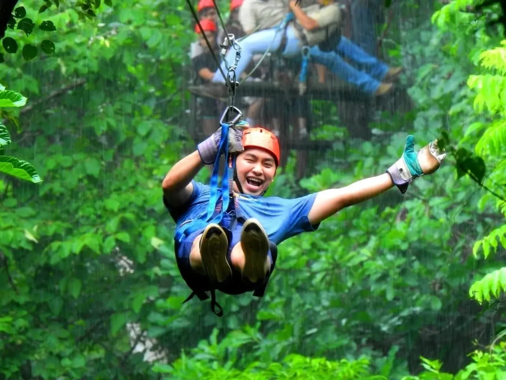 A smiling zipliner soaring through the green jungle canopy on a Guanacaste zipline tour near Playa Potrero
