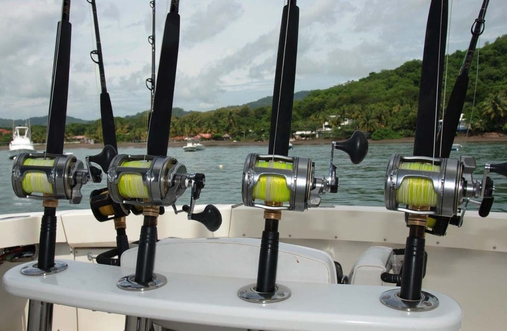 Row of Shimano trolling reels rigged and ready on the Bushwacker charter, with the Playa Flamingo coastline behind