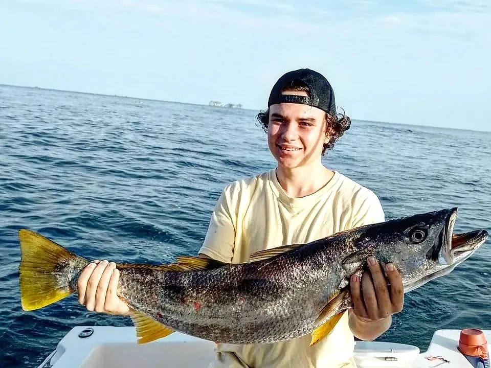 A young angler holding a corvina sea bass caught on the Sea Hunt fishing charter off Playa Potrero, Costa Rica